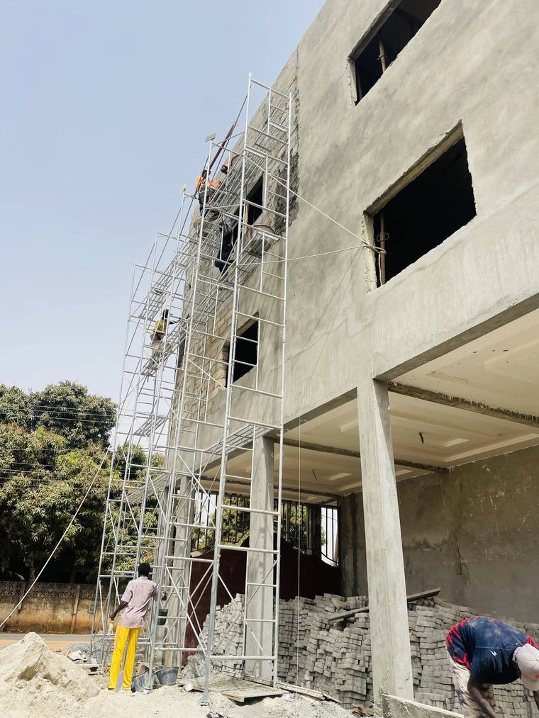 The scaffolded elevation from close in, with blocks stacked at ground level.