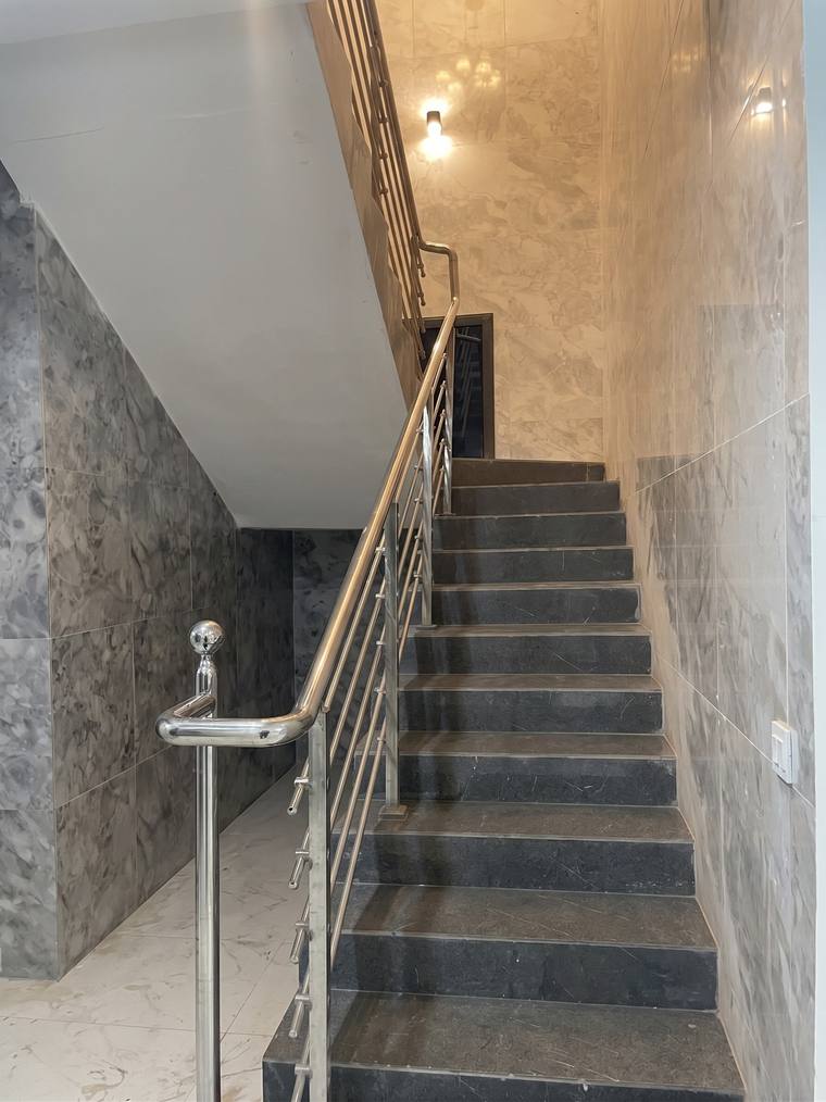 The main staircase, marble-treaded with a stainless steel balustrade rising to the upper floor.