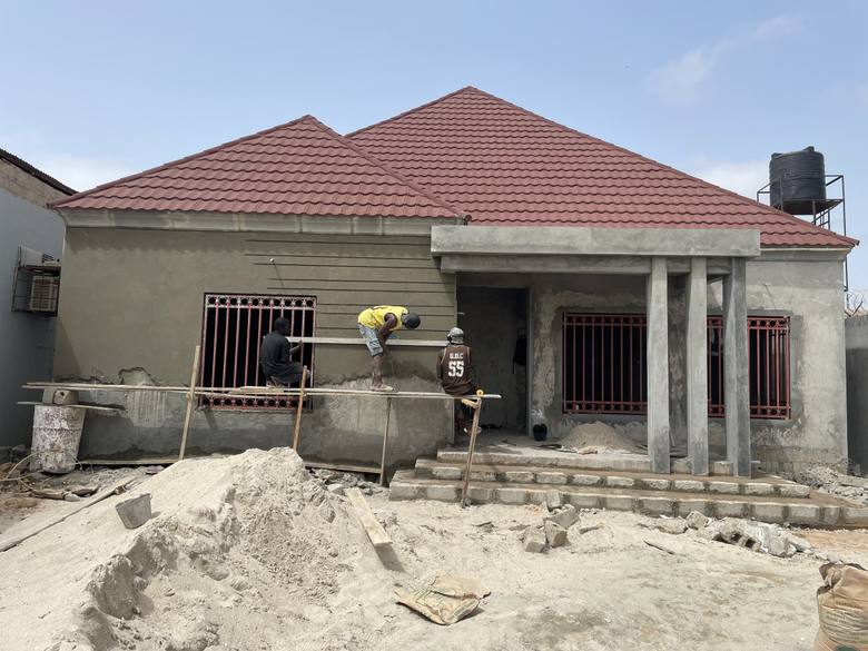 The house with its roof complete and the walls part-rendered, window grilles fitted and the entrance columns cast.